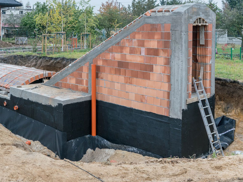 sagu® coating Premiumabdichtung Baugrube mit gemauertem Kellerrohbau, dieser ist abgedichtet mit schwarzer Premiumbeschichtung