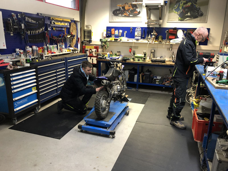 sagu® matting Arbeitsplatzmatten Werkstatt Motorradwerkstatt mit schwarzen Arbeitsplatzmatten auf dem Boden.